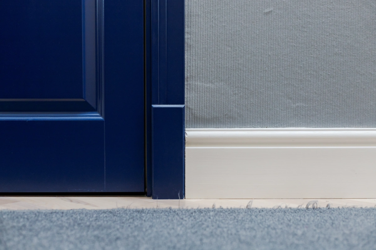 Blue carpet beside a navy interior door and white skirting board