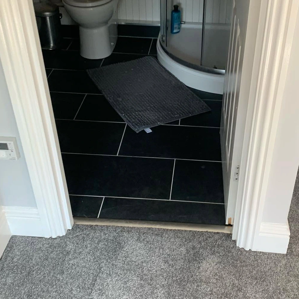 Trimmed bathroom door providing clearance above newly fitted grey carpet