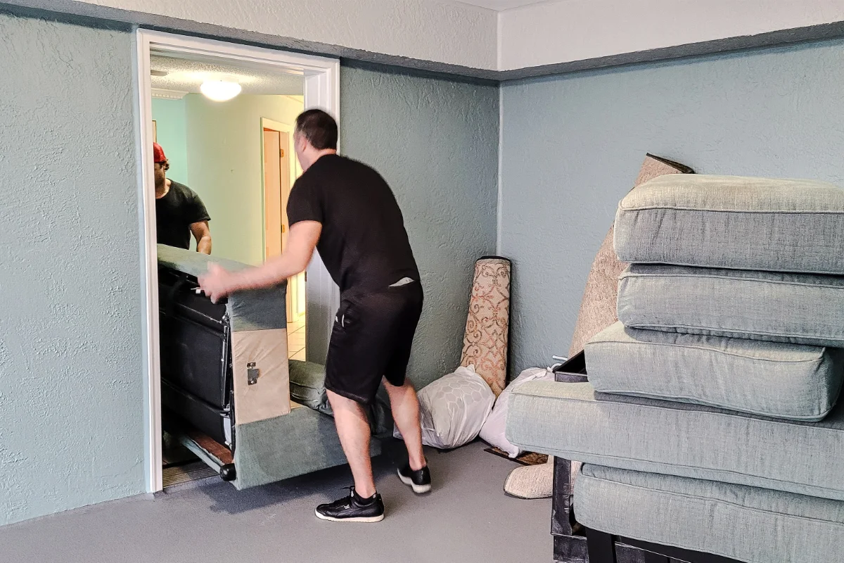 Movers carrying a sofa through a room during a home move