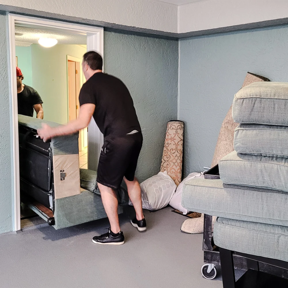 Furniture movers carefully carrying a sofa through an interior doorway