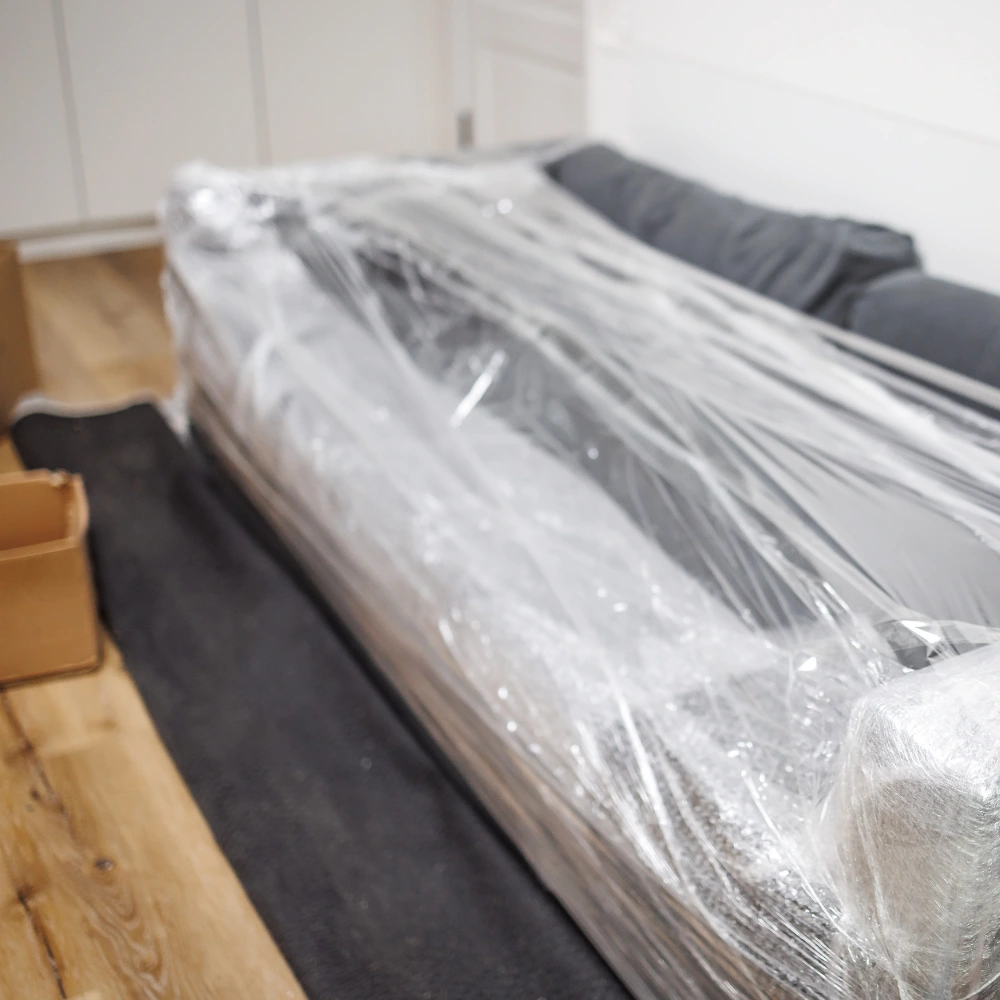 Sofa wrapped in protective plastic ready to be moved during flooring work
