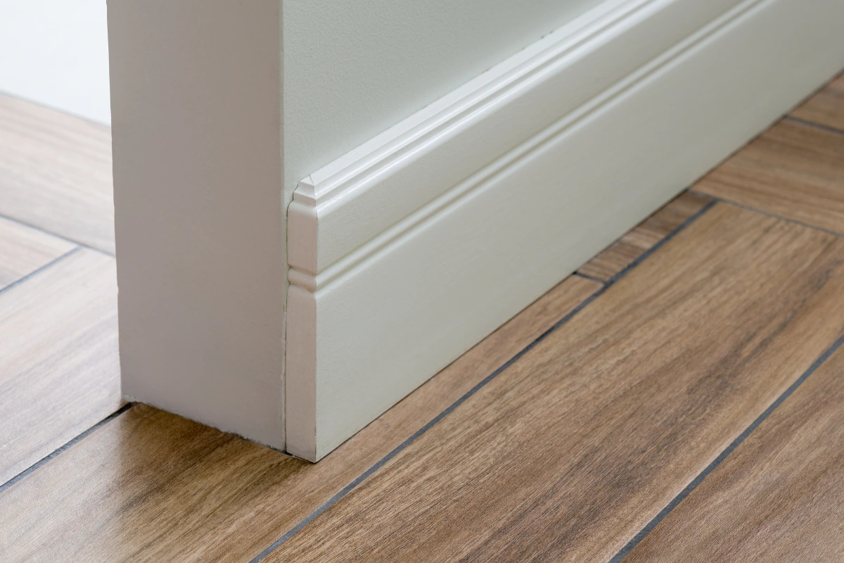 White skirting board fitted above wood-effect flooring