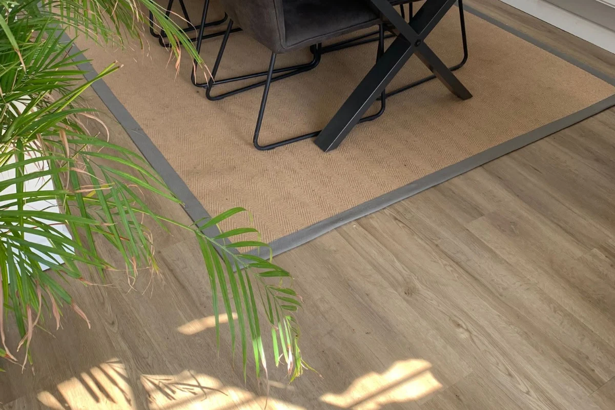 Wood-effect flooring with a bordered carpet inset beneath a dining table