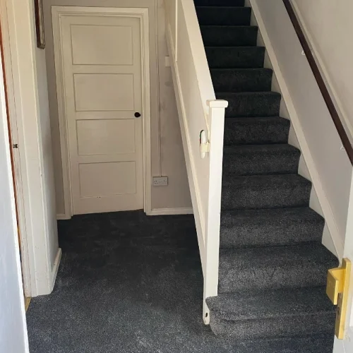 Dark grey carpet fitted throughout a residential hallway and staircase