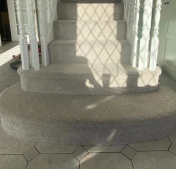 Grey carpet fitted on a curved staircase in a residential hallway