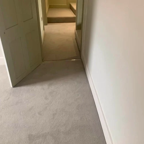 Newly fitted light grey carpet creating a clean, seamless finish through the hallway.