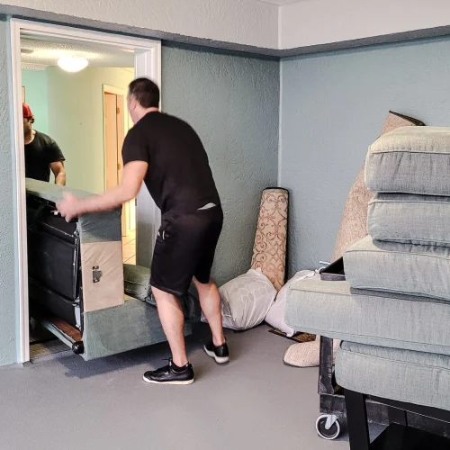 Carpet fitter moving furniture during a residential flooring installation