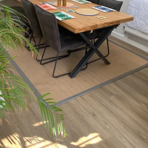 Light wood-effect flooring in a modern dining room with a large area rug